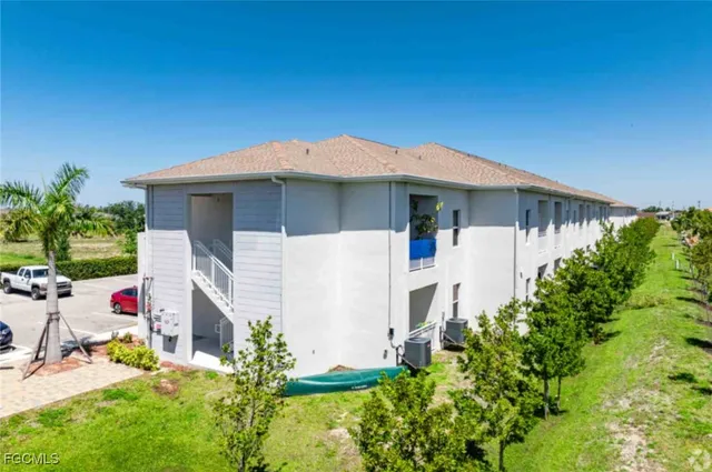 a backyard of a white house with potted plants