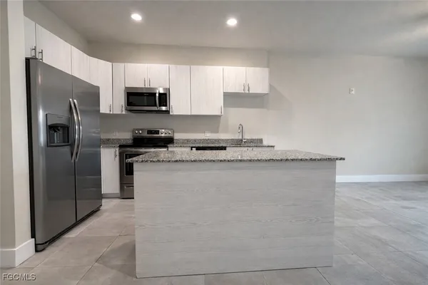 a kitchen with stainless steel appliances granite countertop a refrigerator a stove a microwave and a sink