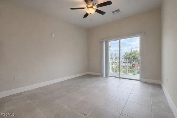 a view of an empty room with chandelier fan and fire place