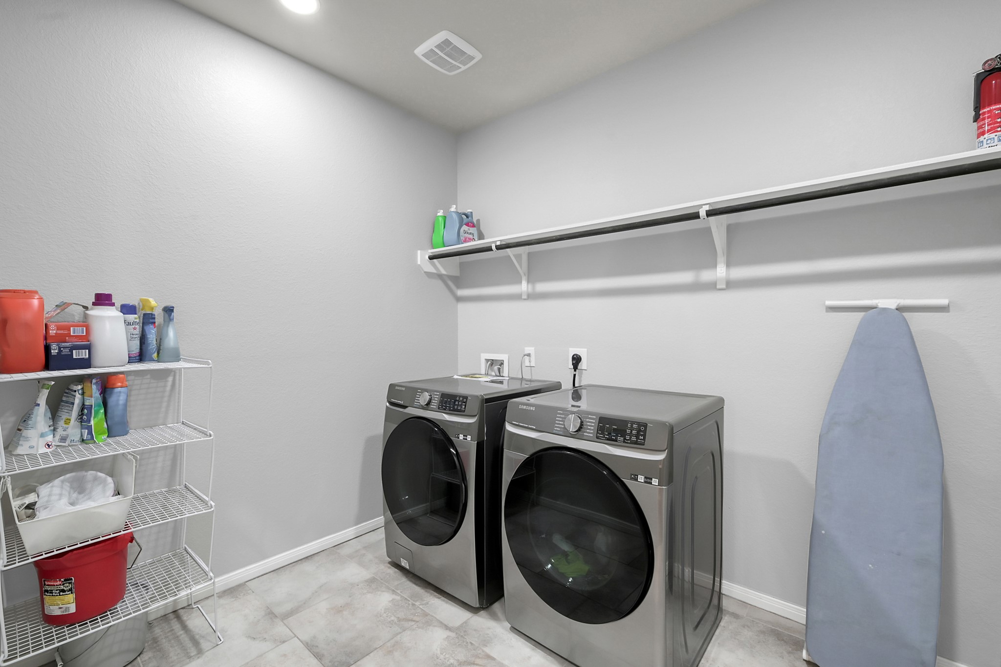 24542 Grayson Falls Lane Spring, TX 77389 - Photo 23 of 48 This large laundry room features modern appliances, open shelving for storage, and tiled flooring, offering a clean and functional space for household chores.