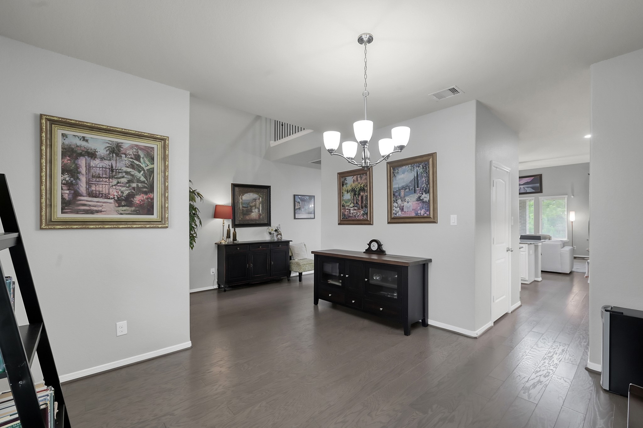24542 Grayson Falls Lane Spring, TX 77389 - Photo 7 of 48 Another view of the spacious, open-plan dinning room area with wood floors and soft gray walls. Ample natural light streams in from large windows, creating a warm and inviting atmosphere.