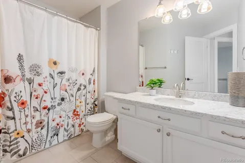 a bathroom with a granite countertop sink a toilet and a shower curtain