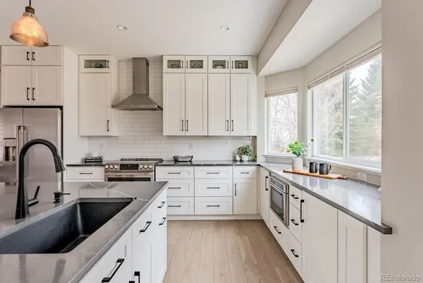 a kitchen with white cabinets a sink a window and appliances