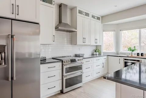 a kitchen with stainless steel appliances granite countertop a stove a refrigerator and a sink