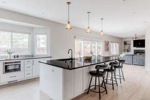 a kitchen with granite countertop a stove a sink a dining table and chairs