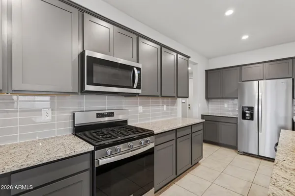 a kitchen with stainless steel appliances granite countertop a stove microwave refrigerator and sink