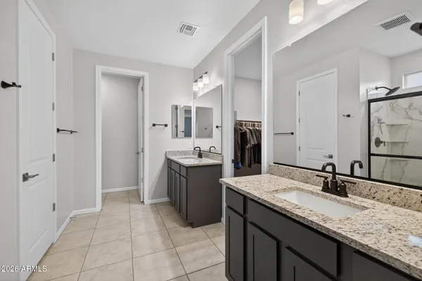 a bathroom with a granite countertop double vanity sink and mirror