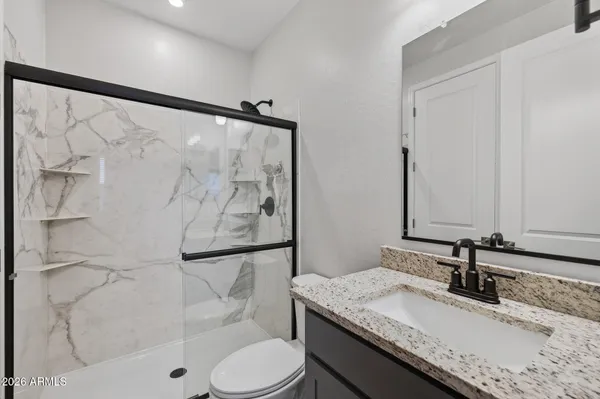 a bathroom with a granite countertop sink toilet and shower