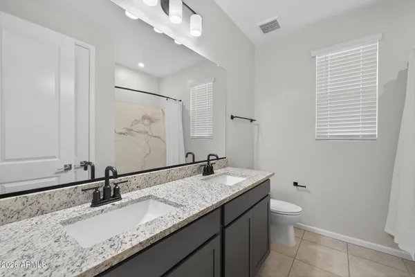 a bathroom with a granite countertop sink a toilet and a mirror