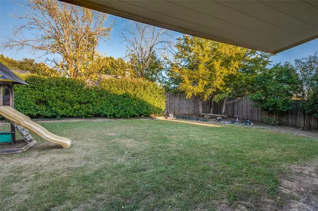 a view of a backyard with plants and wooden fence
