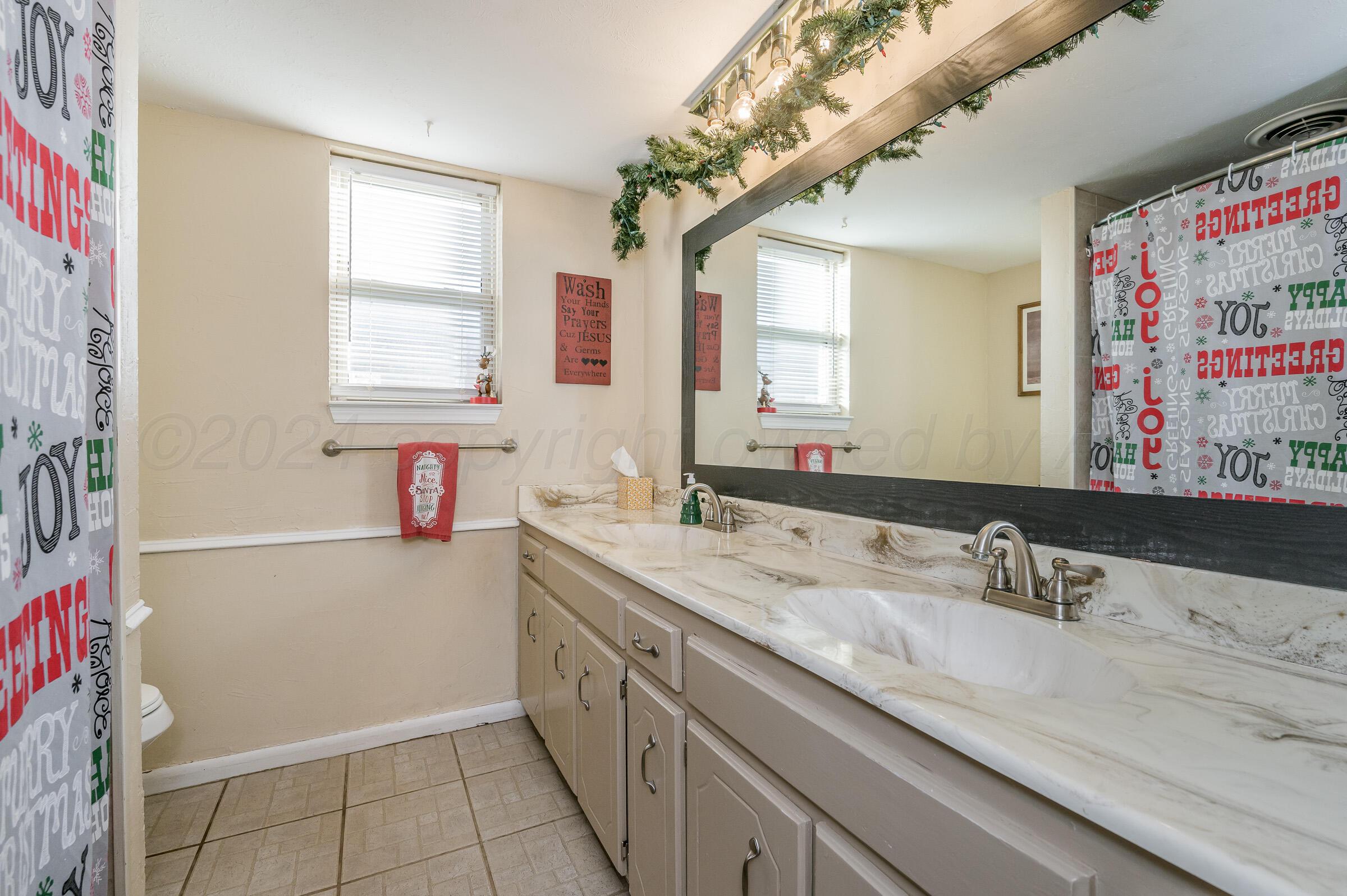 4932 South Georgia Street Amarillo, TX 79110 - Photo 17 of 23 a bathroom with a granite countertop sink a toilet and a mirror