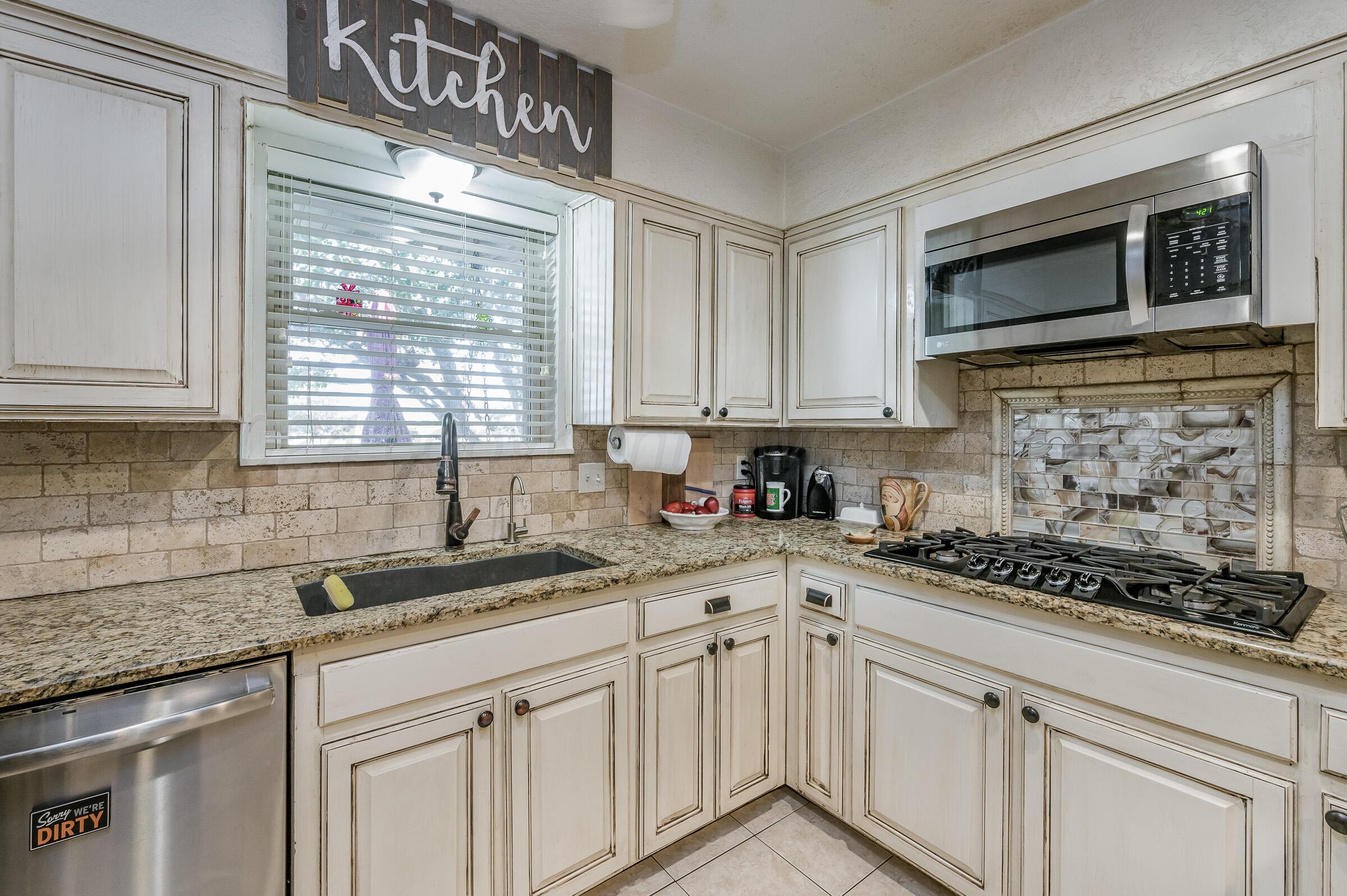 4932 South Georgia Street Amarillo, TX 79110 - Photo 8 of 23 a kitchen with stainless steel appliances granite countertop white cabinets granite counter tops and a window