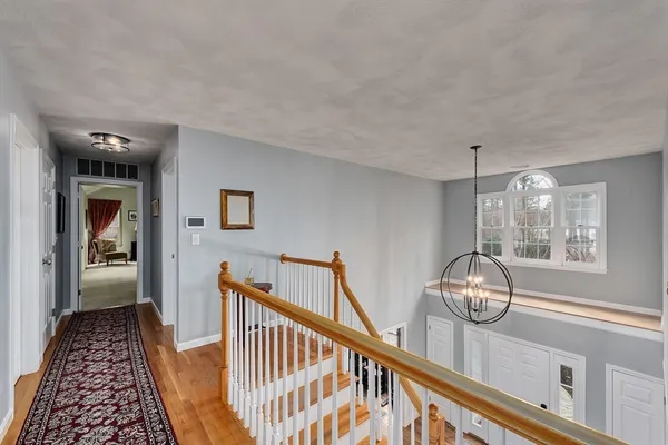 a view of a hallway to a livingroom with wooden floor and windows
