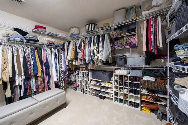 a view of walk in closet with clothes and shoes
