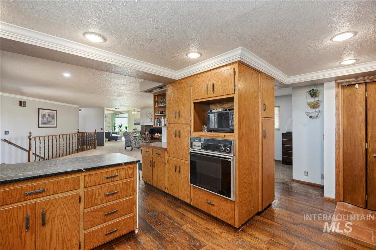 173 Main Line Ranch Road Rupert, ID 83350 - Photo 20 of 47 Kitchen with crown molding, dark wood finished floors, black appliances, a textured ceiling, and brown cabinets