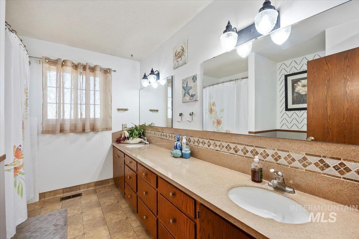 173 Main Line Ranch Road Rupert, ID 83350 - Photo 22 of 47 Full bath featuring curtained shower, double vanity, and backsplash