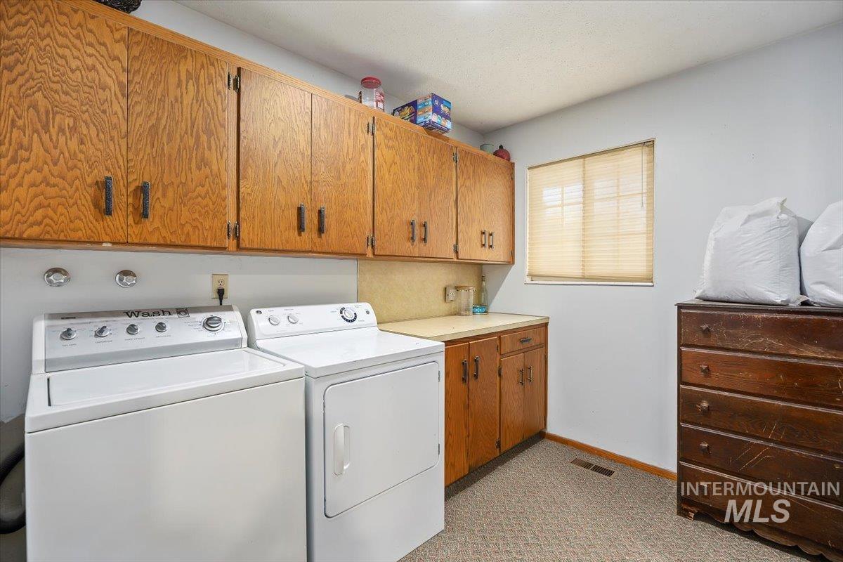 173 Main Line Ranch Road Rupert, ID 83350 - Photo 25 of 47 Laundry room featuring cabinet space, washing machine and dryer, and light carpet