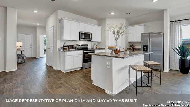 a kitchen with stainless steel appliances a stove a sink a refrigerator white cabinets and wooden floor
