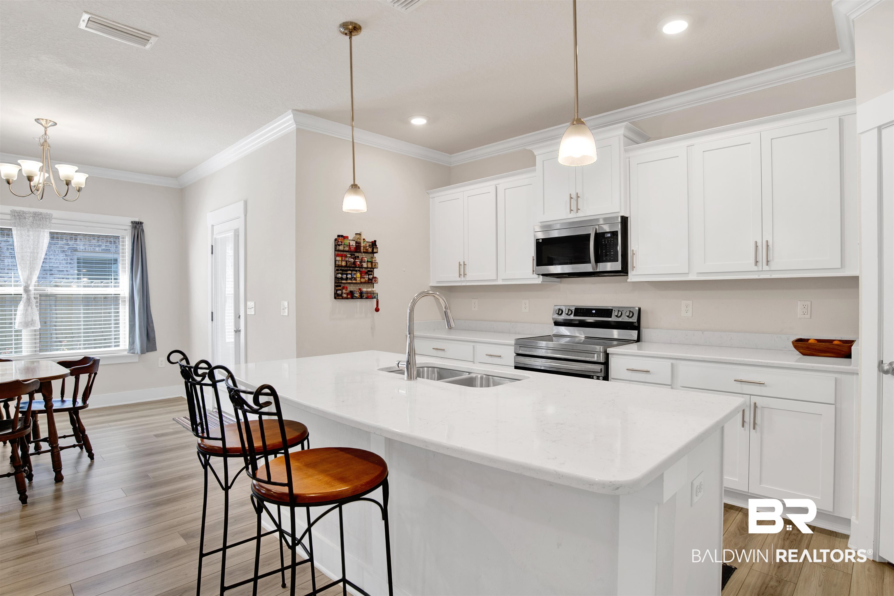 1174 Pheasant Circle Foley, AL 36535 - Photo 11 of 29 Kitchen featuring stainless steel appliances, crown molding, light wood-style floors, white cabinets, and a center island with sink