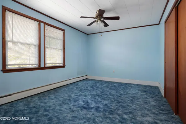 an empty room with chandelier fan and windows