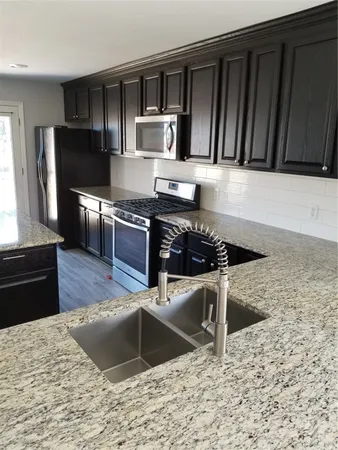 a kitchen with granite countertop a stove a sink and a microwave