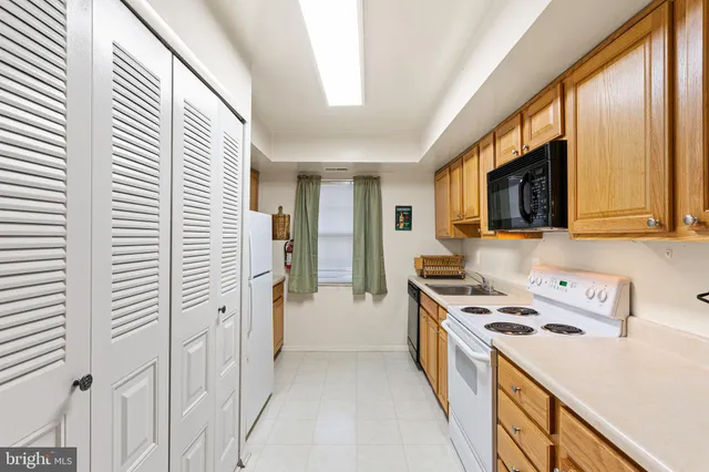 a kitchen with stainless steel appliances a stove top oven a sink a refrigerator white cabinets and wooden floor