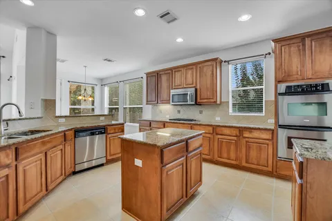 a kitchen with stainless steel appliances granite countertop wooden cabinets a sink and a stove