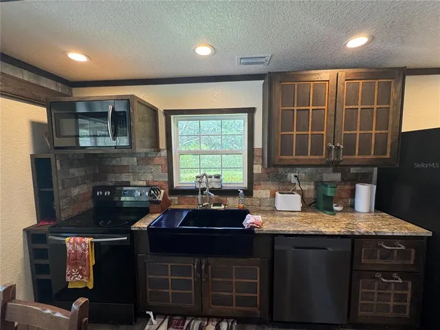 a kitchen with granite countertop a sink stove and cabinets