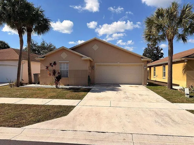 a view of a house with a yard and coconut trees