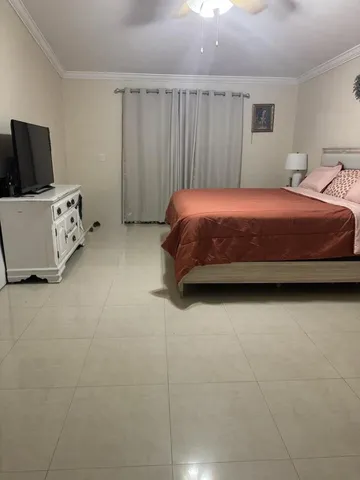 a bedroom with a bed and flat tv screen on the dresser