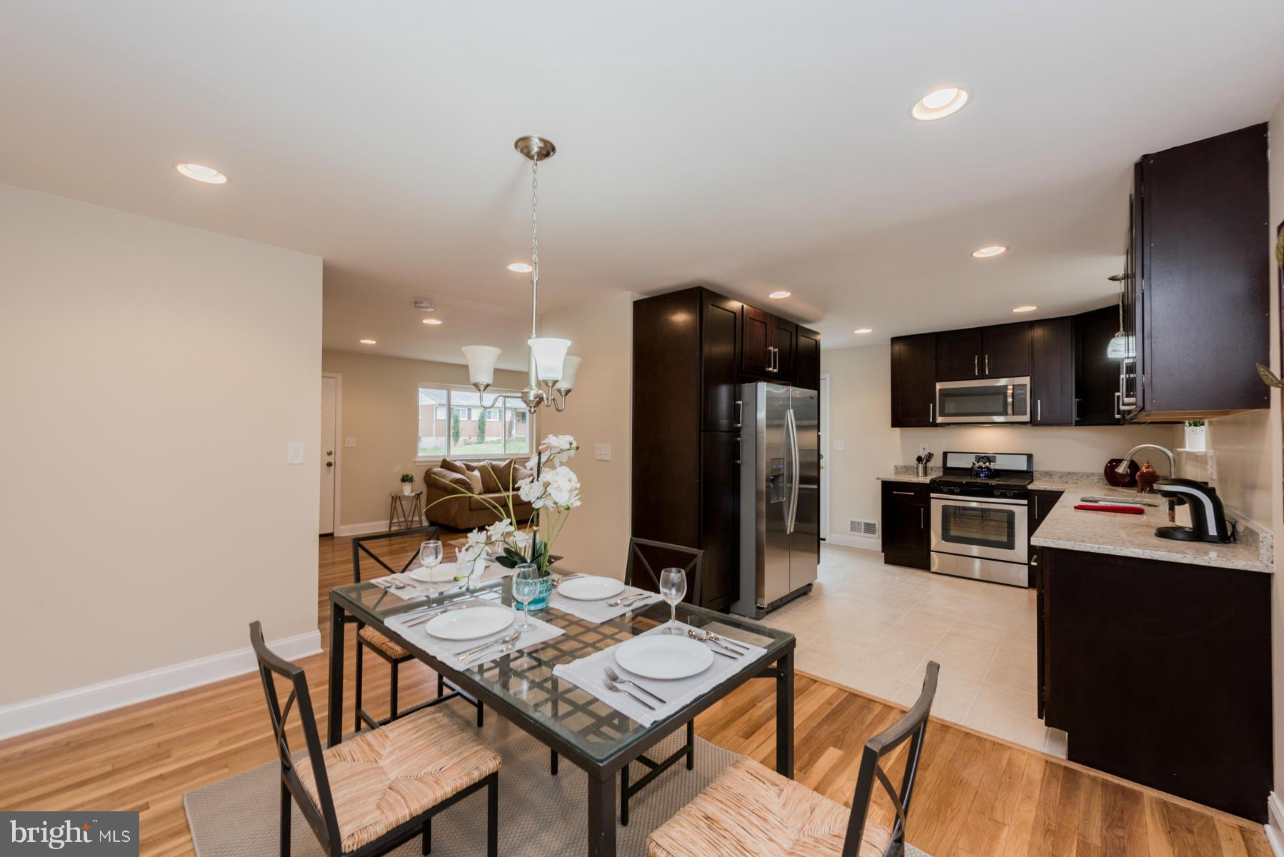 3812 Collier Road Randallstown, MD 21133 - Photo 7 of 27 a kitchen with a dining table cabinets appliances and wooden floor