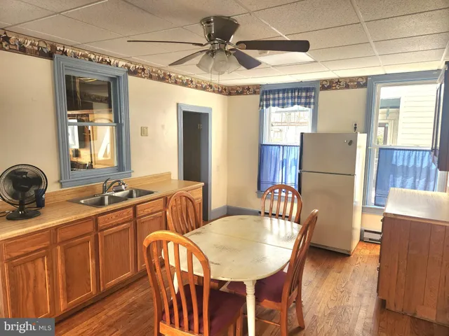 a dining room with wooden floor a chandelier fan a wooden table and chairs
