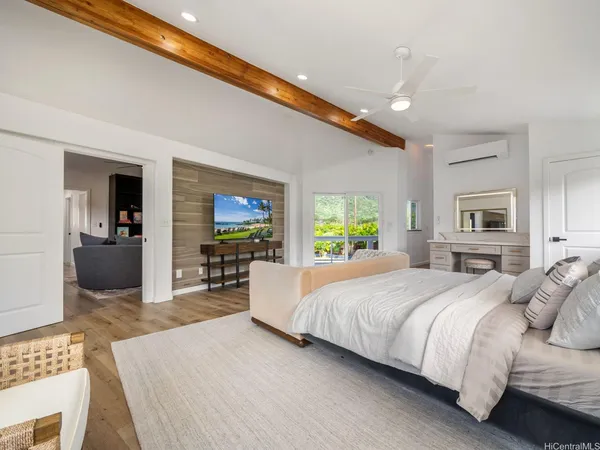 a bedroom with a large bed a flat tv screen and a dresser