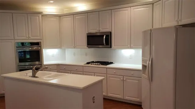 a kitchen with white cabinets and stainless steel appliances