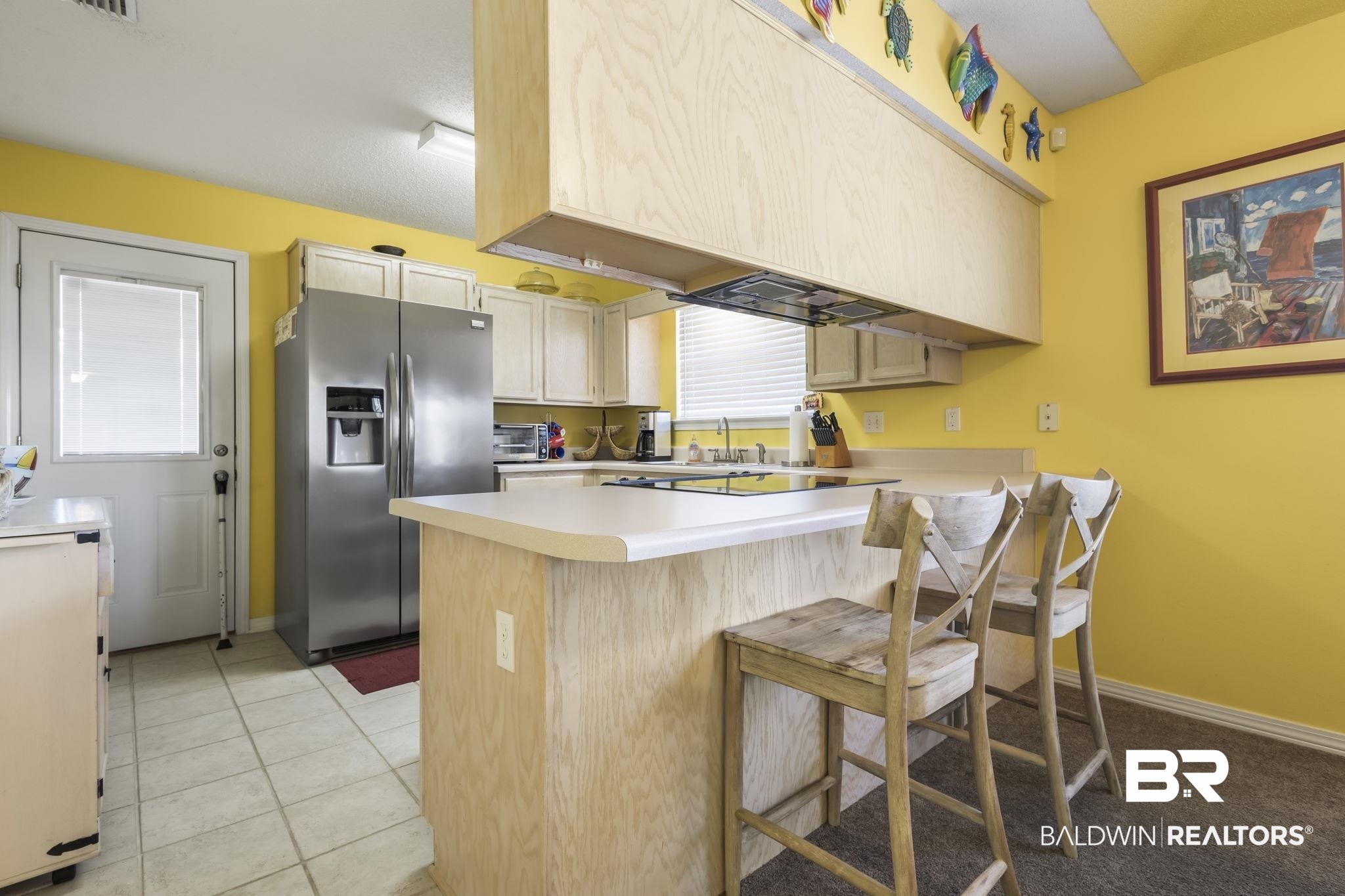 7946 Audubon Drive Foley, AL 36535 - Photo 10 of 25 Kitchen with a kitchen breakfast bar, light tile patterned floors, kitchen peninsula, and stainless steel refrigerator with ice dispenser