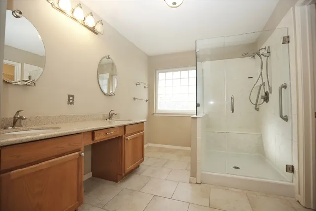 a bathroom with a double vanity sink mirror and shower