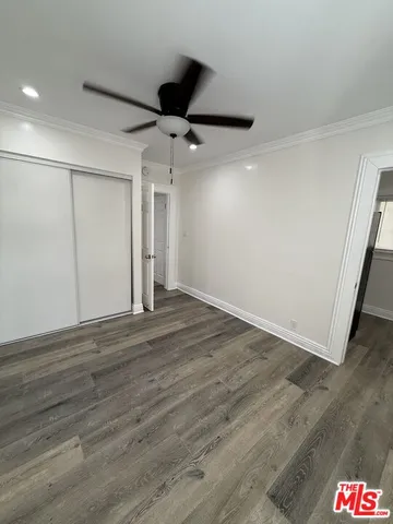 an empty room with wooden floor and ceiling fan