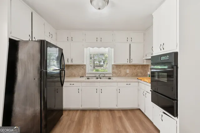 a kitchen with granite countertop white cabinets and refrigerator