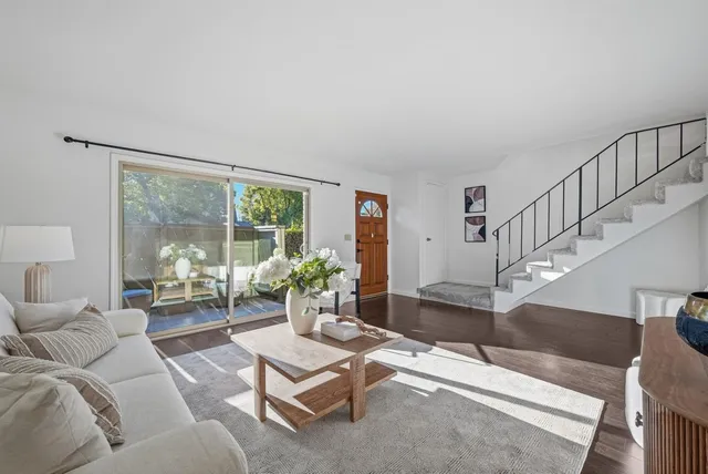 a living room with furniture large windows and wooden floor