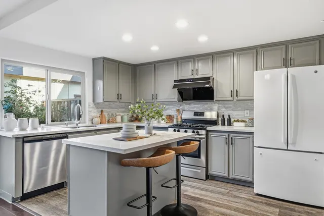 a kitchen with stainless steel appliances a stove a sink refrigerator and a microwave