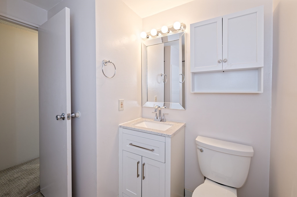 3 Post Oak Lane, Unit 9 Natick, MA 01760 - Photo 22 of 30 a bathroom with a toilet sink vanity and mirror