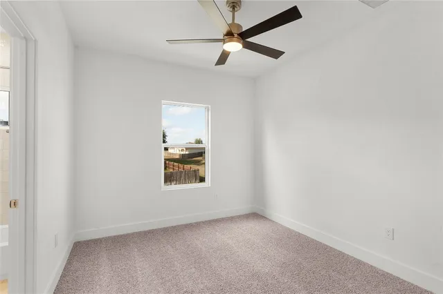 an empty room with a window and a fan