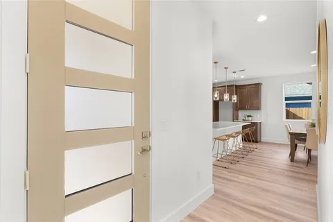 a view of a hallway with wooden floor windows and a living room