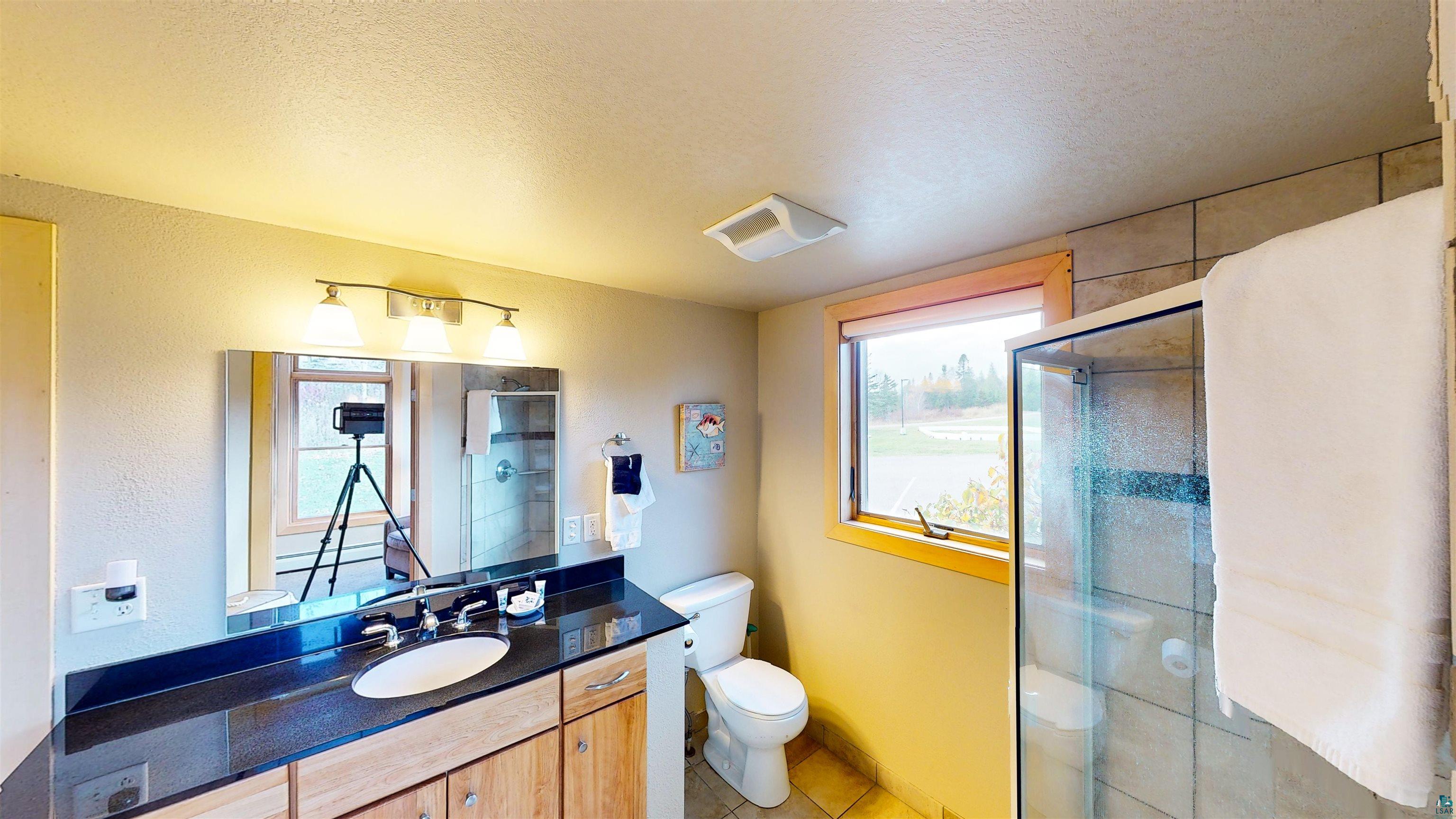 40 Surfside Drive, Unit 5D Tofte, MN 55615 - Photo 34 of 37 Bathroom featuring a single vanity with a dark countertop, an undermount sink, and wood-finish cabinetry