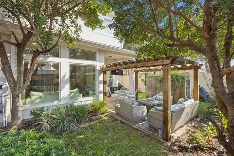 a view of a patio with couches chairs and a large tree