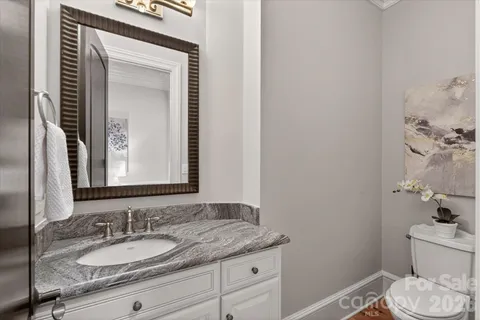 a bathroom with a granite countertop sink and a mirror with toilet
