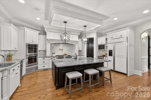 a kitchen with stainless steel appliances kitchen island granite countertop a table chairs sink and cabinets