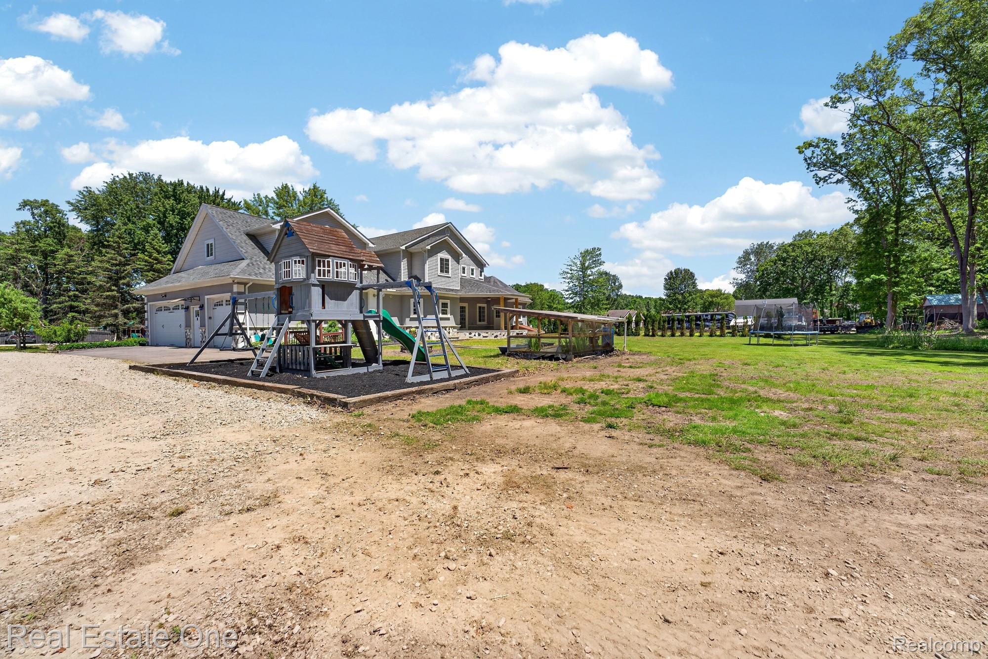 26987 Crawford Road Romulus, MI 48174 - Photo 41 of 51 Expansive property featuring a large backyard with a wooden playset, swings, and slides on a wood chip base