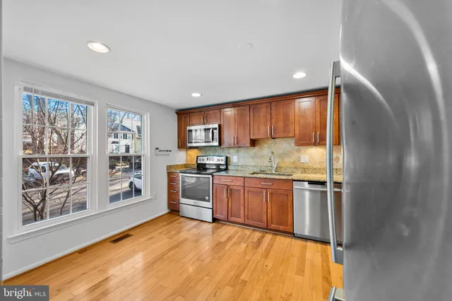 a kitchen with stainless steel appliances granite countertop a refrigerator and wooden cabinets