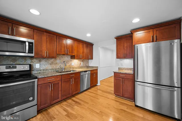 a kitchen with stainless steel appliances granite countertop a refrigerator stove a sink dishwasher and microwave